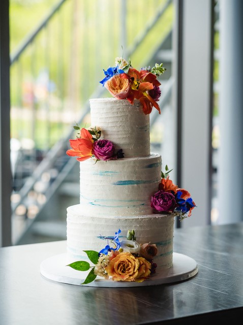 Creme taart met blauwe vegen en kleurrijke bloemen