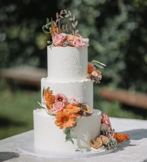 Witte creme bruidstaart met reliëf en verse bloemen