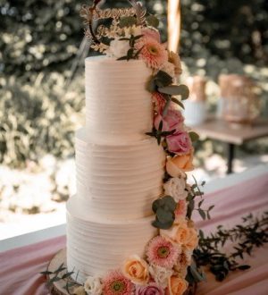 Bruidstaart van creme met strepen en waterval van bloemen