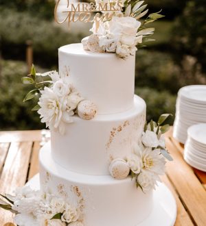 Witte fondant bruidstaart met witte bloemen en gouden accenten