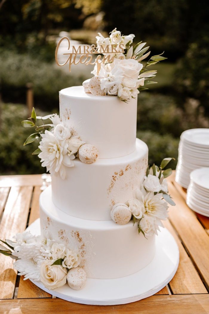 Witte fondant bruidstaart met witte bloemen en gouden accenten