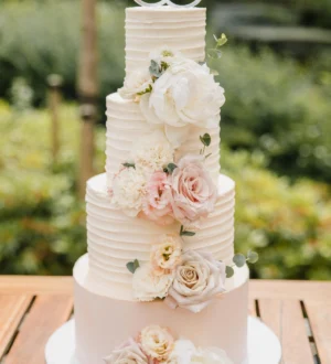 Elegante creme bruidstaart met strepen en verse bloemen Elegante creme bruidstaart met strepen en verse bloemen